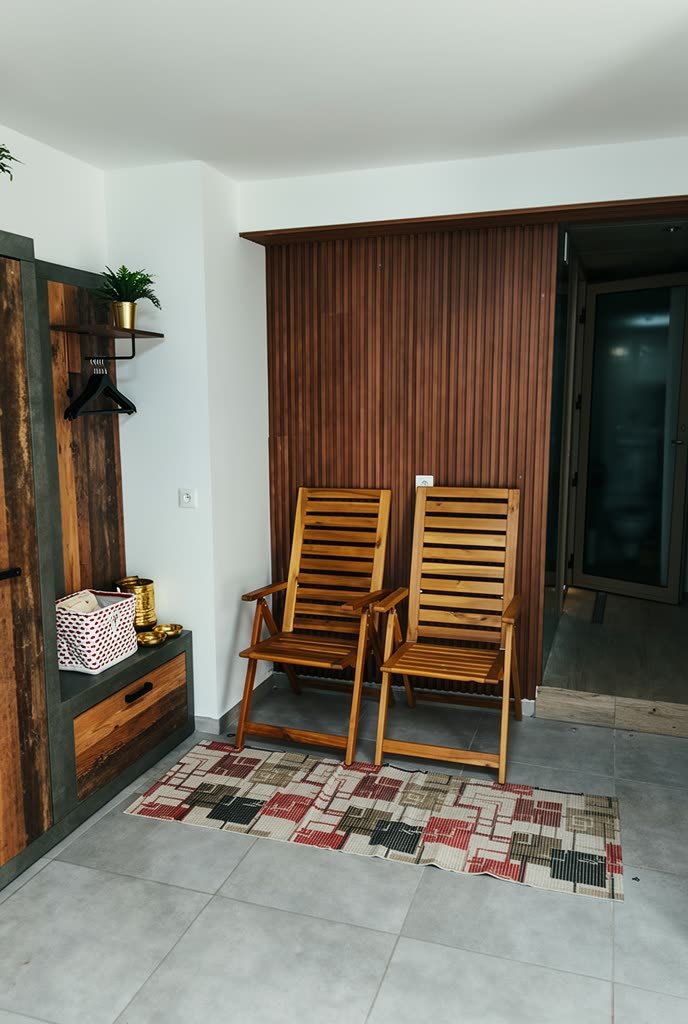 Deux transats en bois dans l’espace de préparation, devant la porte vitrée du hammam.