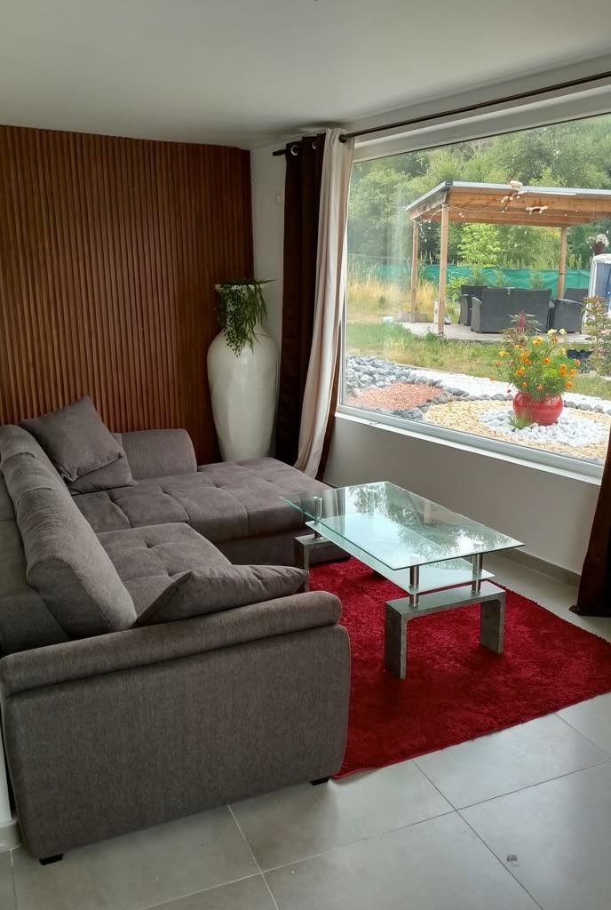 Le salon de repos : canapé et grande baie vitrée ouverte sur le jardin.